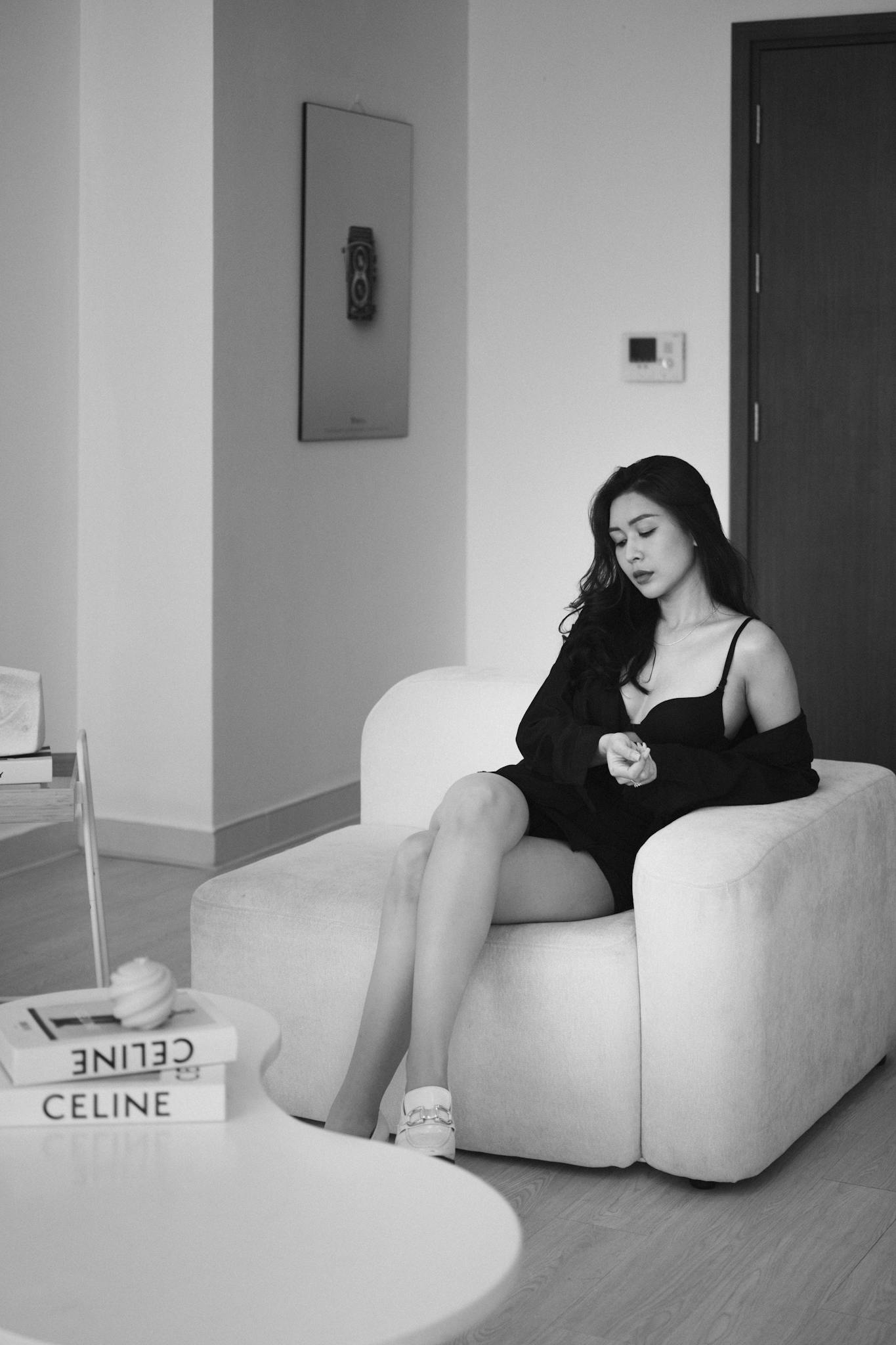 Black and white portrait of a woman seated in a modern room, exuding elegance and tranquility.